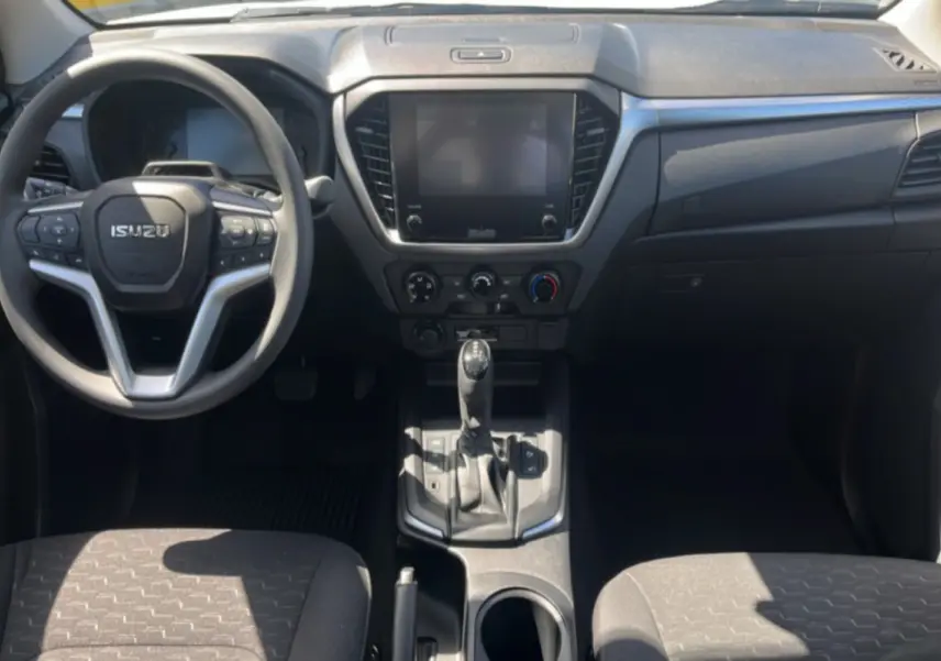 Vue intérieure frontale de l'Isuzu D-MAX 2026 avec tableau de bord noir, écran tactile et volant multifonctions.