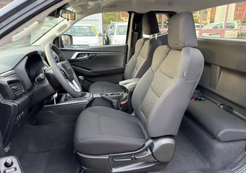 Intérieur avant du pick-up Isuzu D-MAX 2.2 TD 164 Space Evolution, sièges tissu gris et accoudoir central visible.