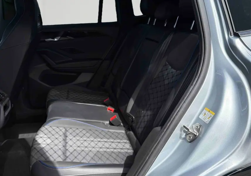 Vue intérieure côté arrière droit du Volkswagen Tiguan 2025, montrant les sièges arrière en cuir noir avec surpiqûres bleues.
