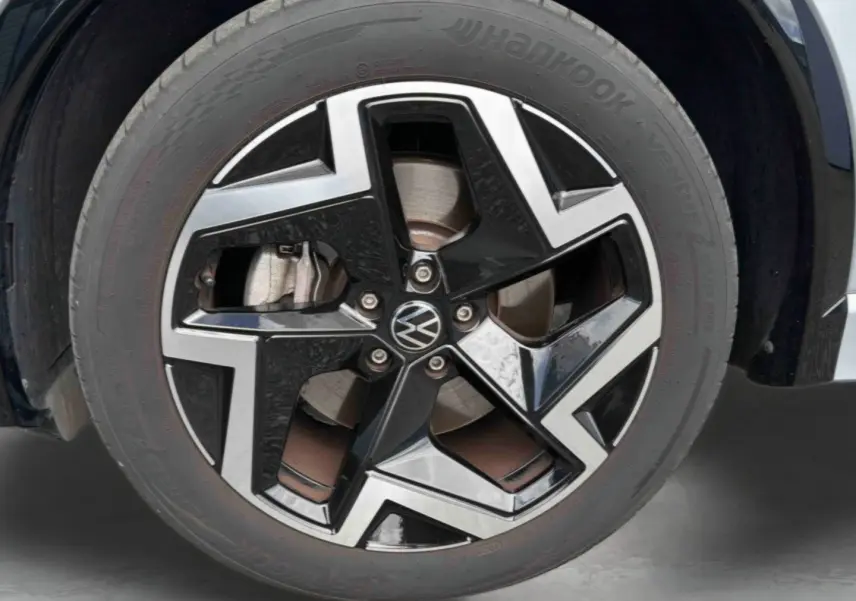 Gros plan sur la jante en alliage noir et argentée du Volkswagen Tiguan gris, mettant en valeur le logo VW central.