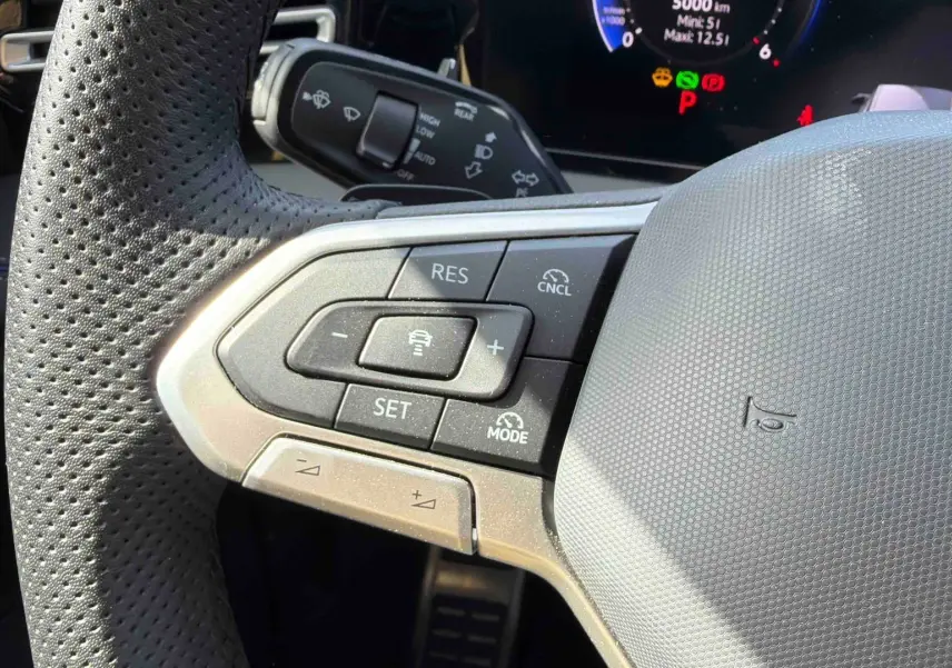 Gros plan sur le volant cuir perforé gris du Volkswagen Tiguan 2025 avec commandes du régulateur adaptatif.