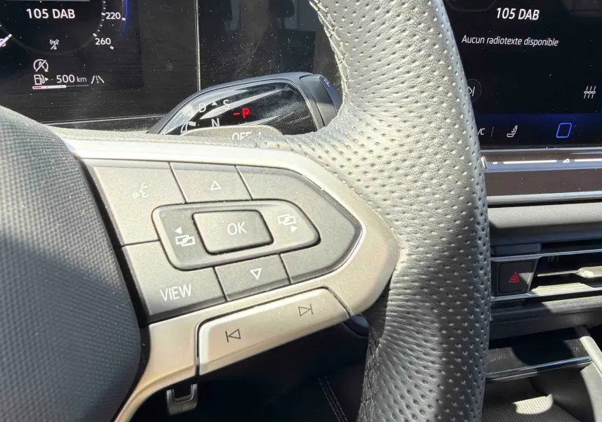 Gros plan sur le volant cuir perforé et les commandes multifonctions du Volkswagen Tiguan 2025, intérieur noir.