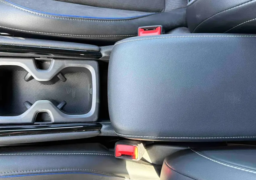 Vue plongeante sur la console centrale grise du Volkswagen Tiguan 2025 avec accoudoir et porte-gobelets noirs.