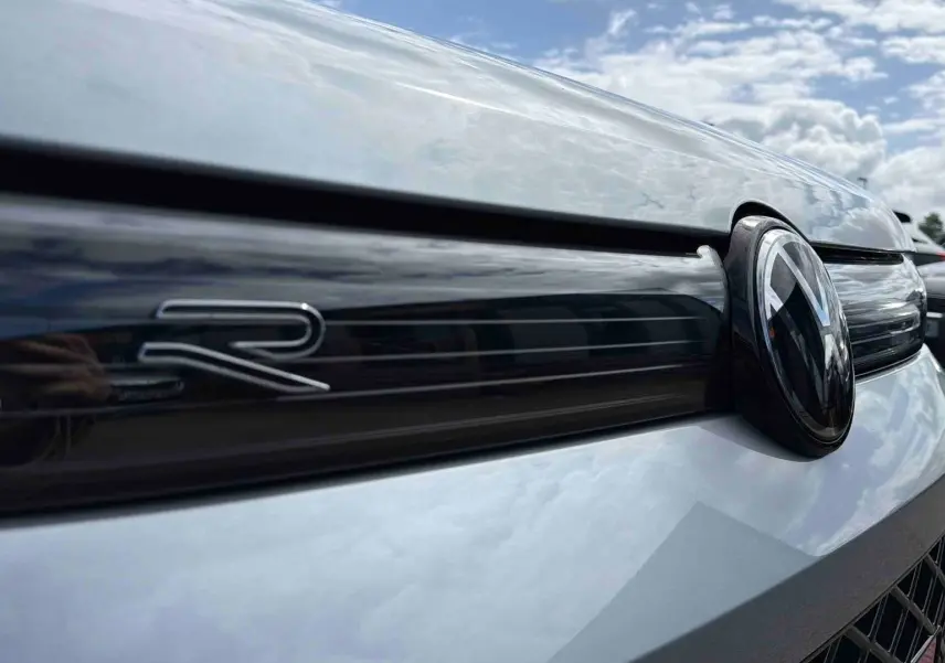 Gros plan sur la calandre avant grise du Volkswagen Tiguan 2025 avec logo VW et sigle R noir brillant.