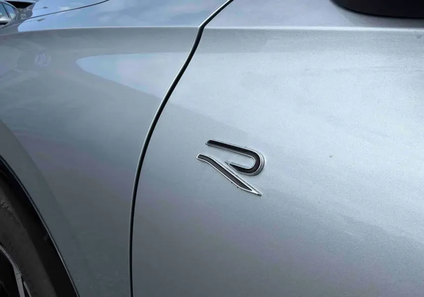Détail du logo R sur l'aile avant gauche d'un Volkswagen Tiguan gris métallisé, avec jante noire visible.