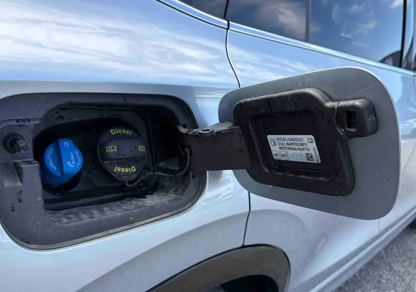 Gros plan sur la trappe à carburant ouverte côté gauche d’un Volkswagen Tiguan gris 2025 avec bouchon diesel visible.
