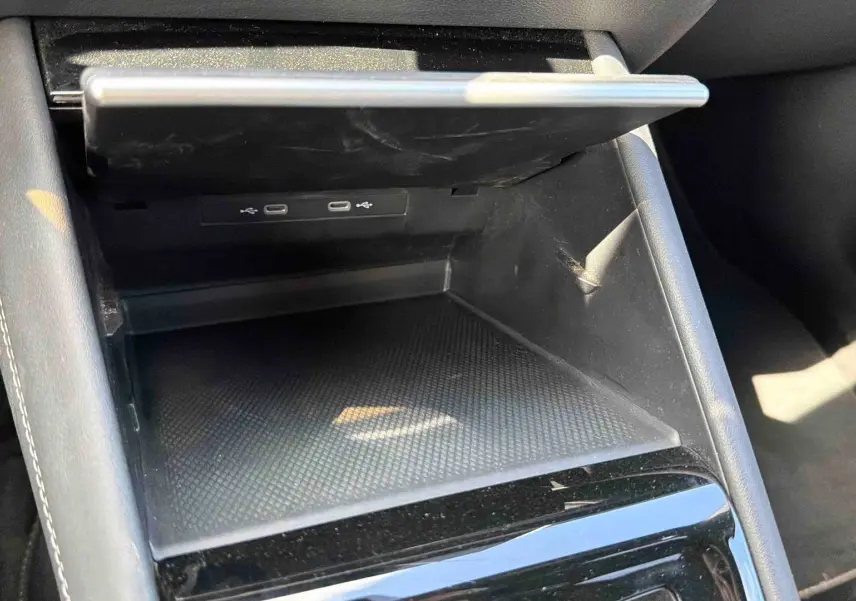 Rangement central ouvert avec deux ports USB-C visibles, intérieur noir mat et garniture cuir gris clair.