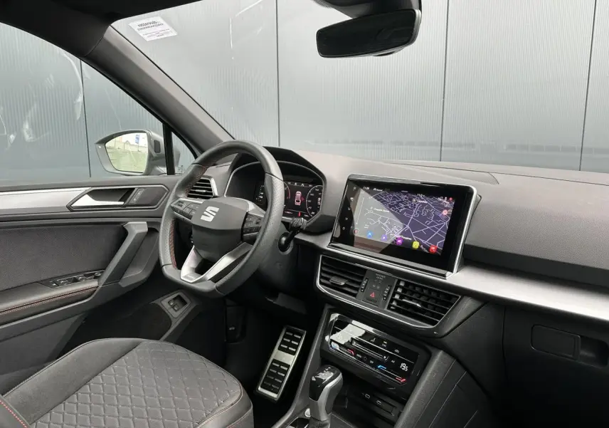 Intérieur côté conducteur du SEAT Tarraco blanc, volant cuir multifonction et écran tactile avec navigation visible.