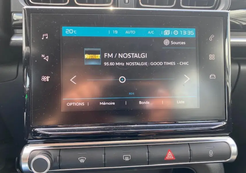 Écran tactile central de la Citroën C3 gris clair de 2017 affichant la radio FM Nostalgie et les commandes climatisation.