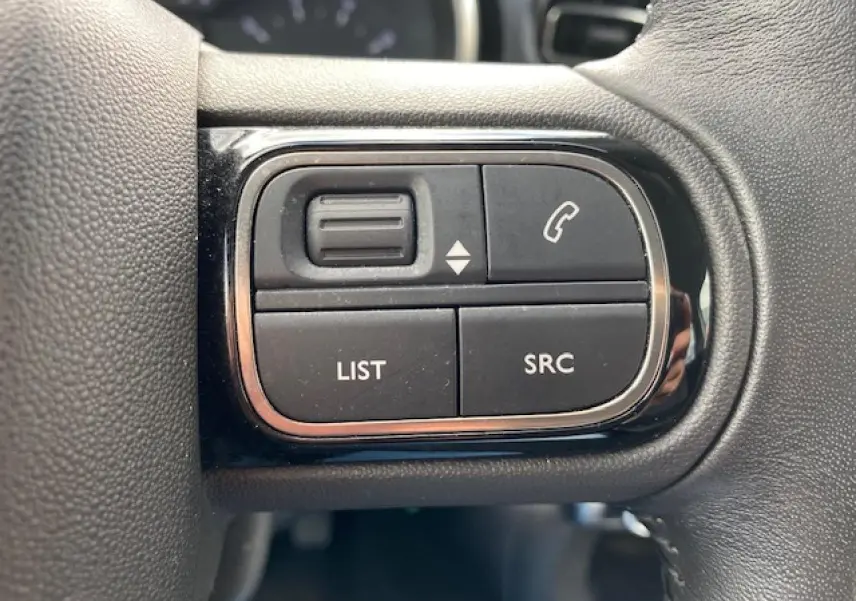 Gros plan sur les commandes au volant du Citroën C3 gris clair 2017, boutons pour téléphone et liste audio.