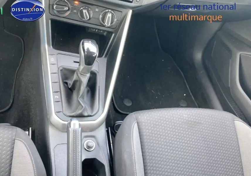 Vue intérieure centrée sur la console centrale et levier de vitesse d'une Volkswagen Polo 1.0 TSI gris cendre, sièges tissu noir.