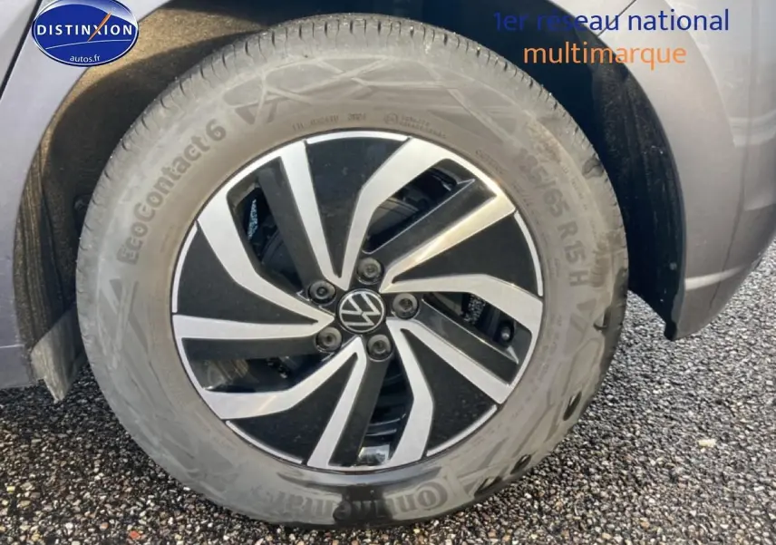 Gros plan sur la jante alliage 15 pouces noire et argentée du côté avant droit d'une Volkswagen Polo gris cendre.