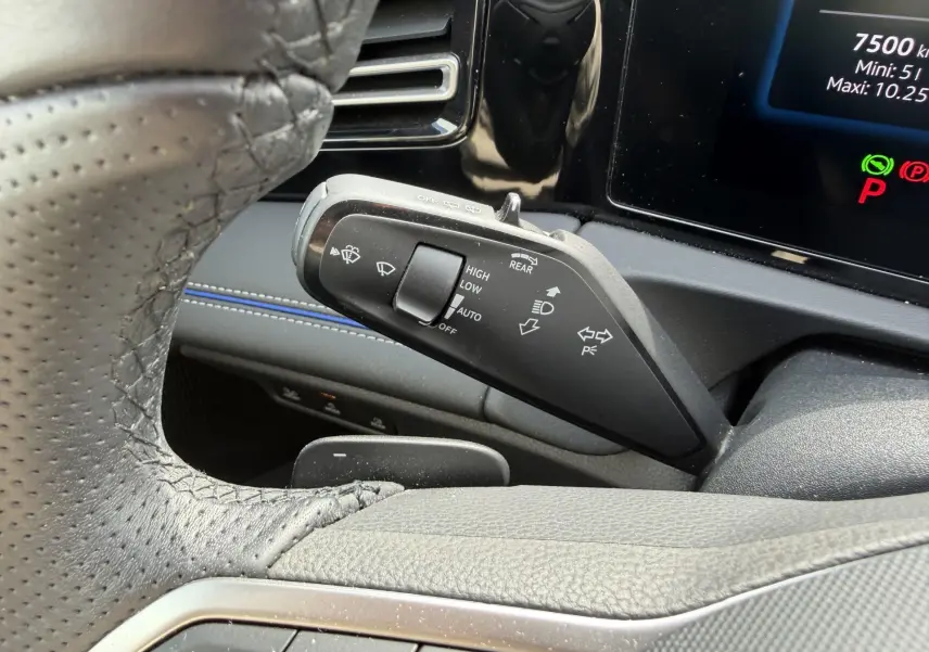 Gros plan sur la manette de commandes des essuie-glaces et clignotants du Volkswagen Tiguan 2025, intérieur noir avec surpiqûres bleues.