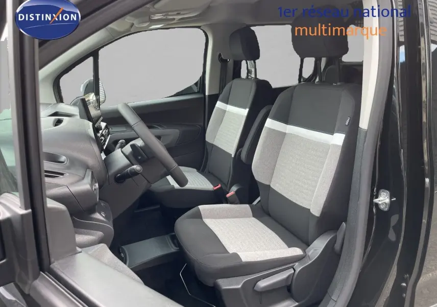 Vue intérieure côté conducteur du Citroën Berlingo noir Perla Nera, mettant en valeur les sièges tissu bicolores gris et noir.