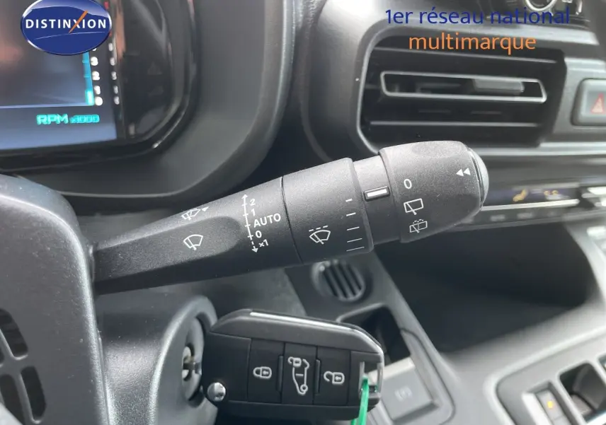 Gros plan sur la commande d’essuie-glace et la clé insérée dans le contacteur d’un Citroën Berlingo noir, intérieur côté gauche.