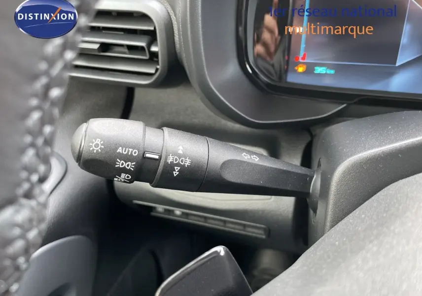 Gros plan sur la commande des feux et clignotants à gauche du volant dans le tableau de bord noir du Citroën Berlingo noir Perla Nera.