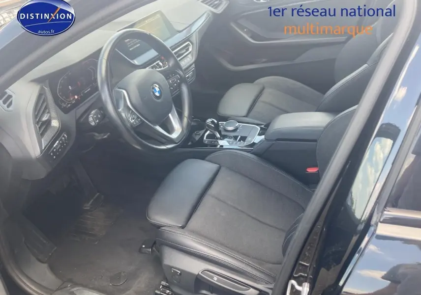 Intérieur avant côté conducteur d'une BMW Série 1 noire 2023, sièges sport en tissu et cuir, volant multifonction cuir.