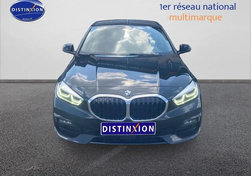 Vue frontale d'une BMW Série 1 noire 2023 avec phares LED allumés et calandre double haricot distinctive.