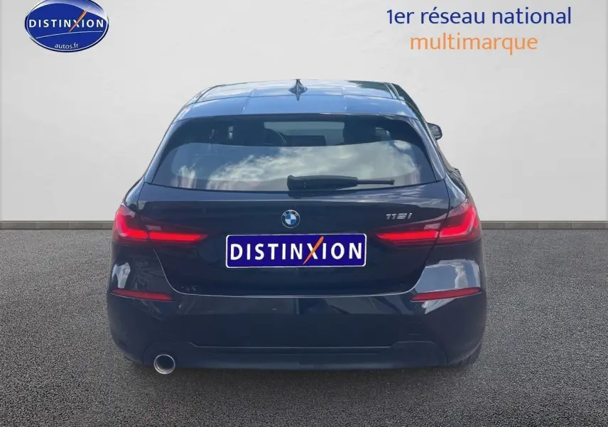 Vue arrière d'une BMW Série 1 noire (118i) avec feux LED allumés sur fond neutre.