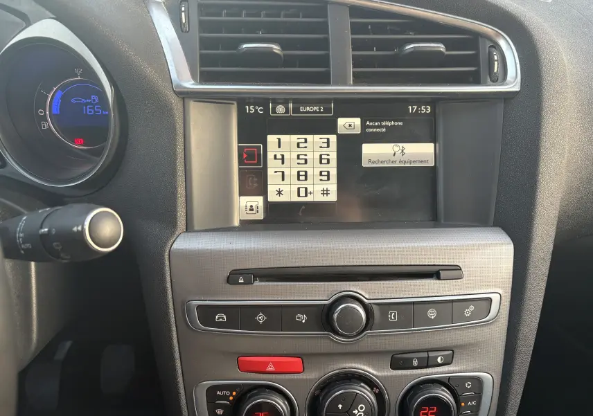 Vue rapprochée du tableau de bord de la Citroën C4 II diesel hybride 2015 avec écran tactile et commandes de climatisation.