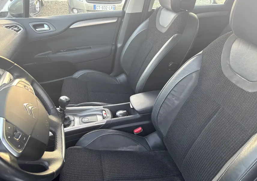 Intérieur noir de la Citroën C4 II 2.0 HDI 150 HYB 2015, vue côté conducteur avec volant et levier de vitesse manuel.