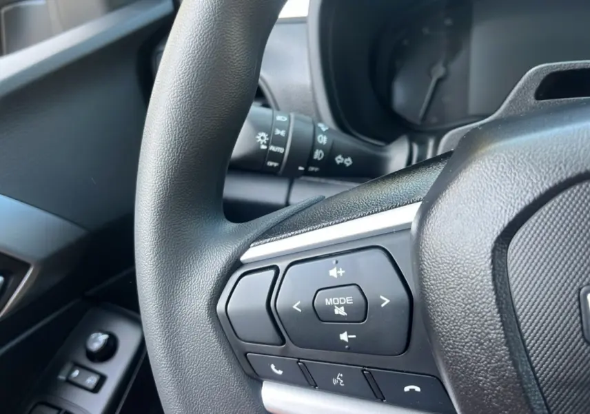 Gros plan sur le volant multifonctions côté gauche de l'Isuzu D-MAX 2026, boutons de commande audio et téléphone visibles.