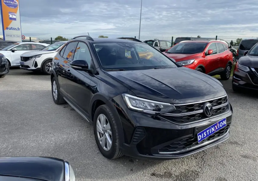 Volkswagen Taigo noir intense vu en 3/4 avant droit sur parking avec calandre et phares LED visibles.