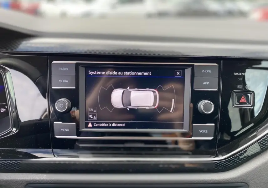 Écran tactile central du Volkswagen Taigo 2022 affichant l'aide au stationnement dans un intérieur noir brillant.
