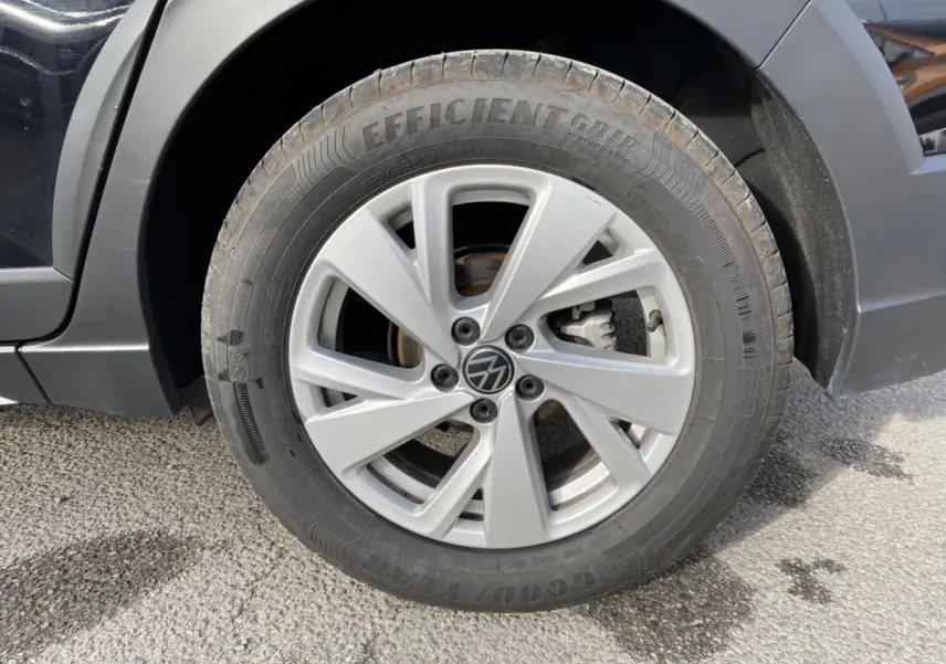 Gros plan sur la roue avant gauche du Volkswagen Taigo noir intense, mettant en valeur la jante alliage et le pneu Goodyear.