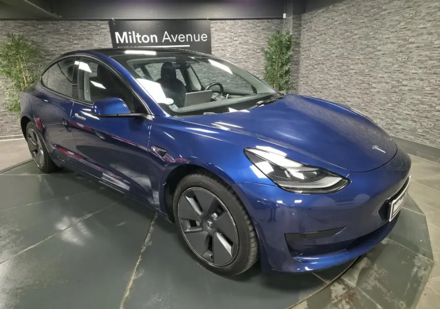 Tesla Model 3 RWD bleu foncé vue 3/4 avant droit, avec jantes 18 pouces et poignées couleur carrosserie.