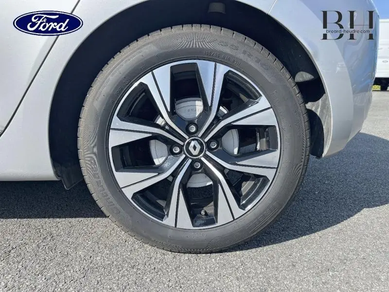 Gros plan sur la roue avant droite gris platine d'une Renault Clio 1.6 E-Tech hybride 2023 avec jante alu bicolore.