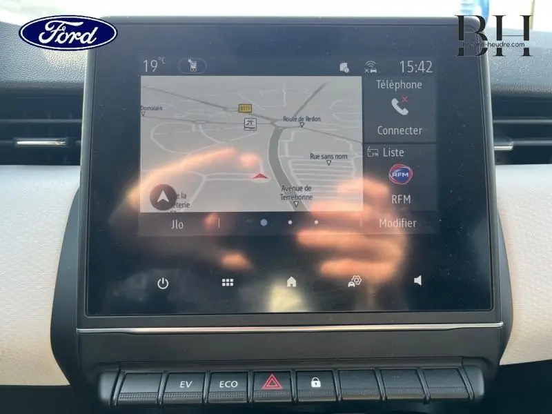 Écran tactile central du tableau de bord de la Renault Clio 1.6 E-Tech gris platine, affichant le GPS en navigation.