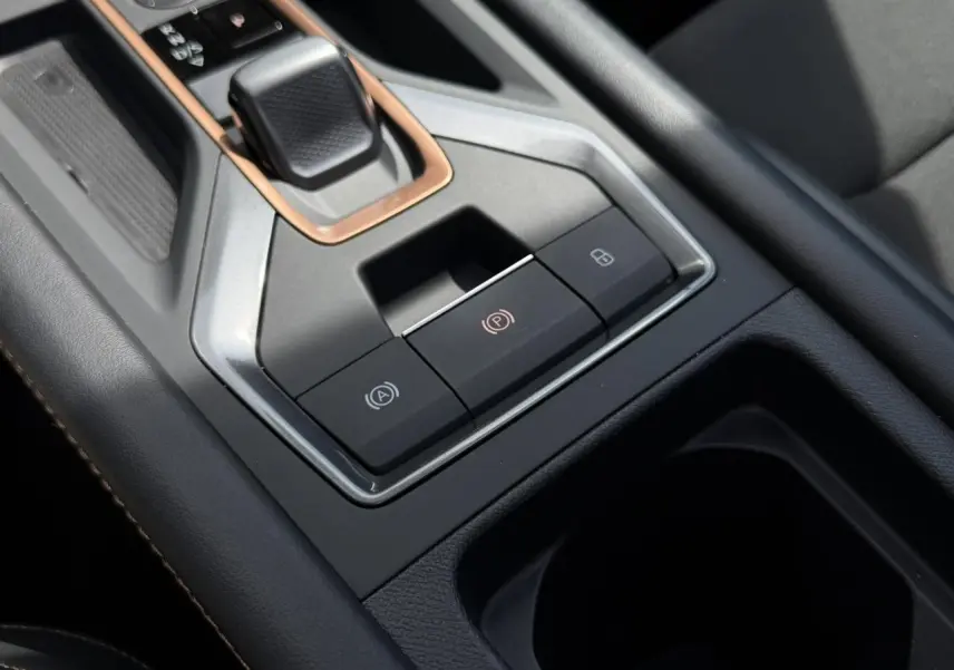 Gros plan sur la console centrale noire du CUPRA Formentor blanc, avec commandes électroniques et insert cuivré autour du levier.