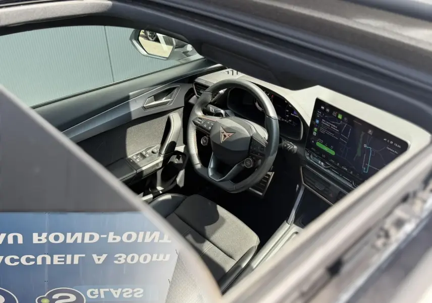 Vue intérieure par le toit ouvrant panoramique montrant le volant Supersports CUPRA et l’écran tactile HD du Formentor blanc.