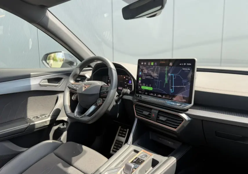 Vue intérieure avant droite du CUPRA Formentor blanc neige, avec tableau de bord numérique et écran tactile central lumineux.