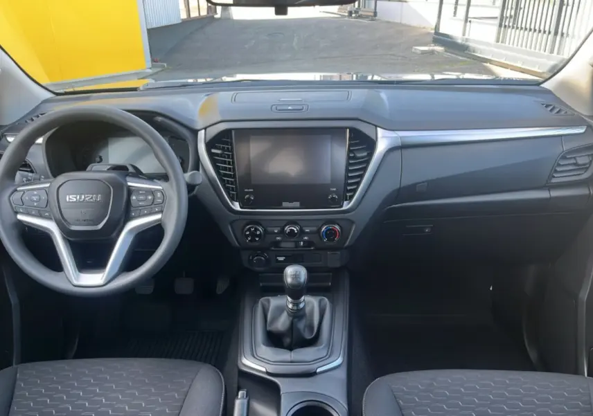 Vue intérieure avant de l'Isuzu D-MAX 2026 avec tableau de bord noir et volant multifonctions.