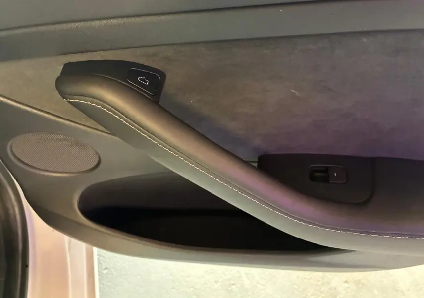 Détail de la poignée intérieure côté gauche de la porte d’une Tesla Model 3 blanche, version 2023.