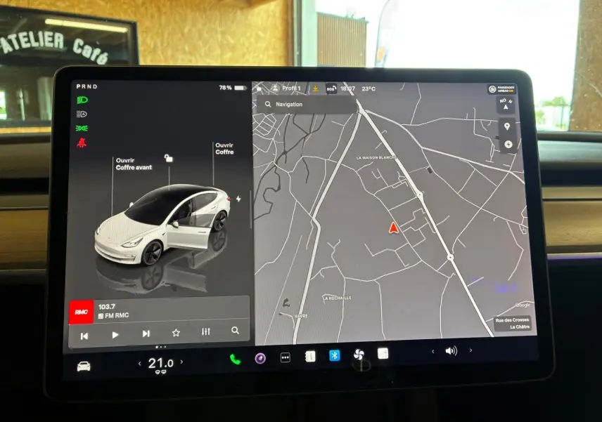 Écran tactile intérieur de Tesla Model 3 blanc, vue frontale de la voiture sur l'interface avec carte de navigation affichée.