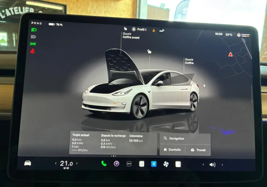 Écran tactile montrant une Tesla Model 3 blanche en 3/4 avant avec capot et coffre ouverts, interface de contrôle.
