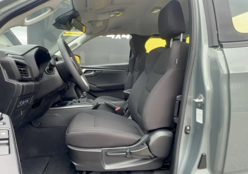 Intérieur côté conducteur du pick-up Isuzu D-MAX 2026 vert Inishmore, sièges tissu noirs et volant multifonctions.