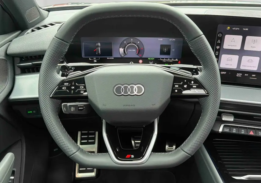 Vue intérieure centrée sur le volant sport cuir gris avec logo S, tableau de bord numérique et écran tactile Audi Q3 Sportback.