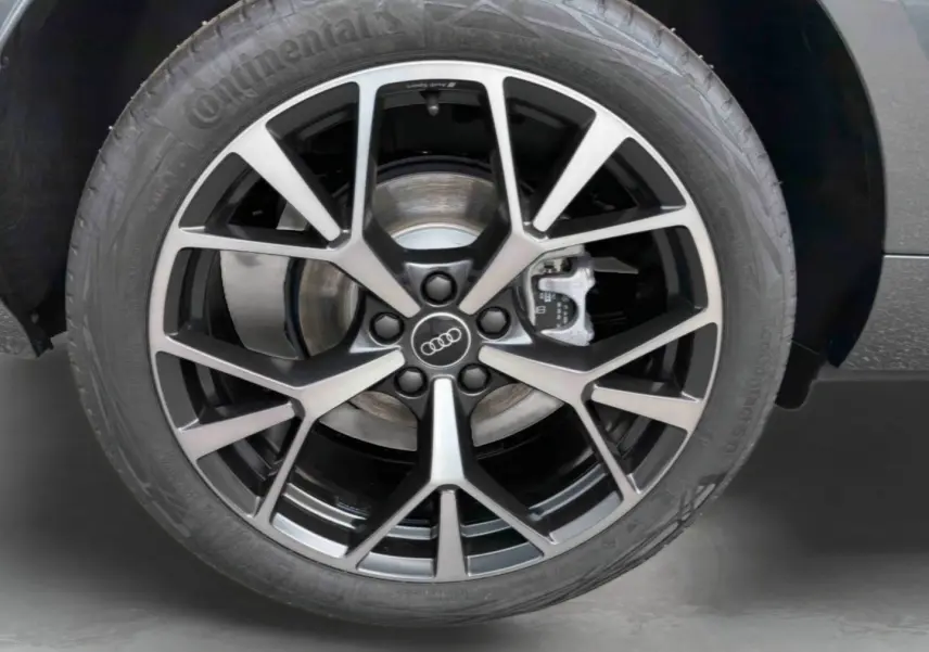 Gros plan sur la jante Audi Sport style tripode à 5 branches noires métalliques du Q3 Sportback gris.