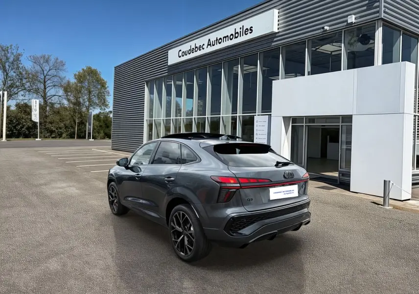 Audi Q3 Sportback gris vue 3/4 arrière droit, avec jantes noires et toit ouvrant panoramique visible.