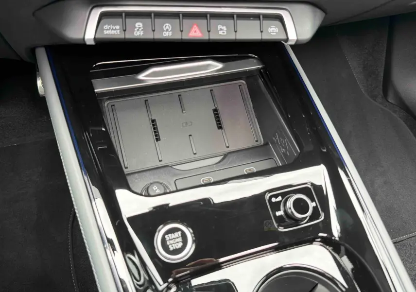 Vue rapprochée de la console centrale noire brillante de l’Audi Q3 Sportback 2026 avec boutons et zone de recharge sans fil.
