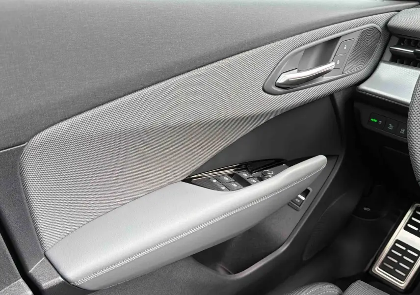 Détail de la porte avant gauche grise de l'Audi Q3 Sportback avec commandes de vitres et poignée chromée.