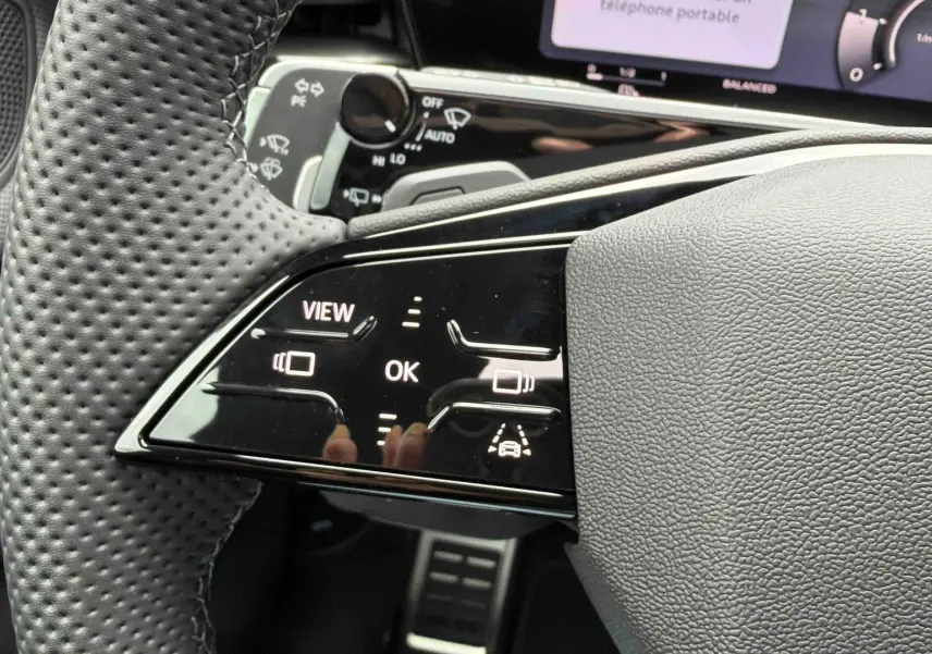 Gros plan sur le volant cuir perforé côté gauche de l’Audi Q3 Sportback gris avec commandes tactiles et affichage numérique.