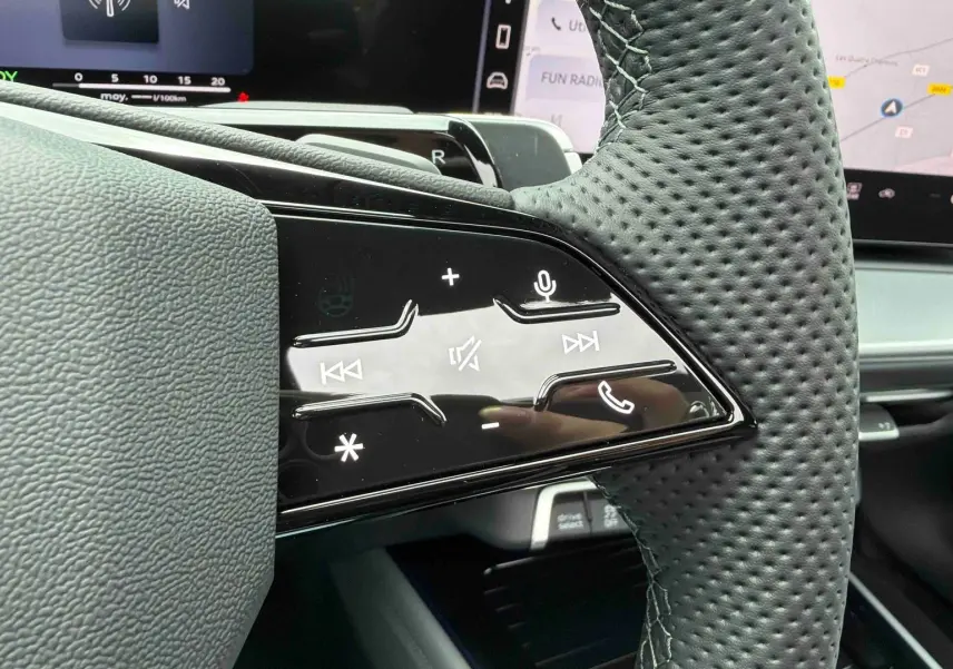 Gros plan sur les commandes tactiles noires du volant perforé côté gauche de l’Audi Q3 Sportback gris.