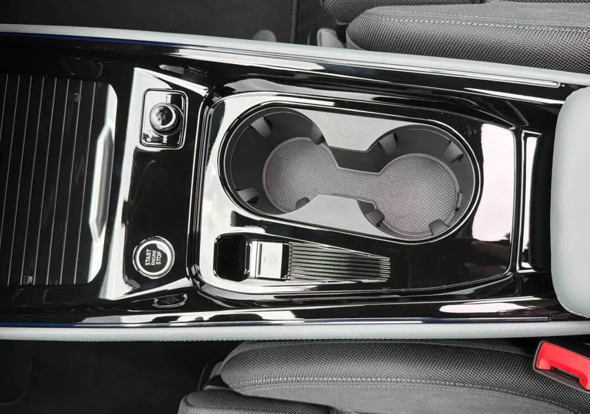 Gros plan sur la console centrale noire brillante avec porte-gobelets et bouton start/stop de l'Audi Q3 Sportback gris.