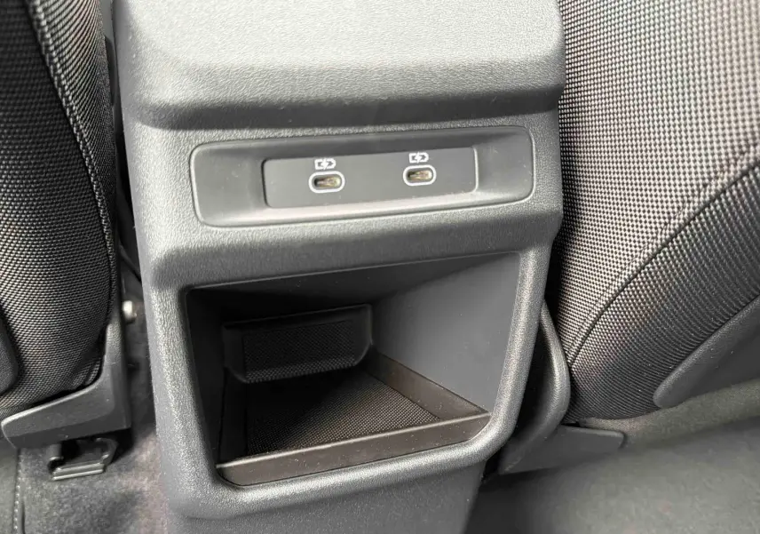 Gros plan sur la console arrière avec deux ports USB-C et rangement, entre les sièges noirs du Q3 Sportback gris.