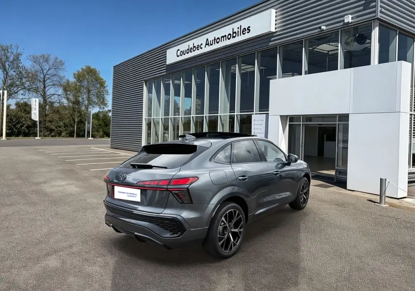 Vue 3/4 arrière droite d'un Audi Q3 Sportback gris métallisé avec jantes noires devant un bâtiment moderne.